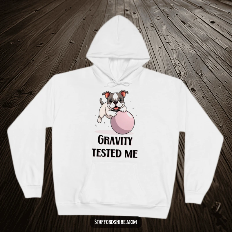 Funny Staffordshire Bull Terrier hoodie showing a dog mid-trip over a huge ball, great for staying warm and laughing.