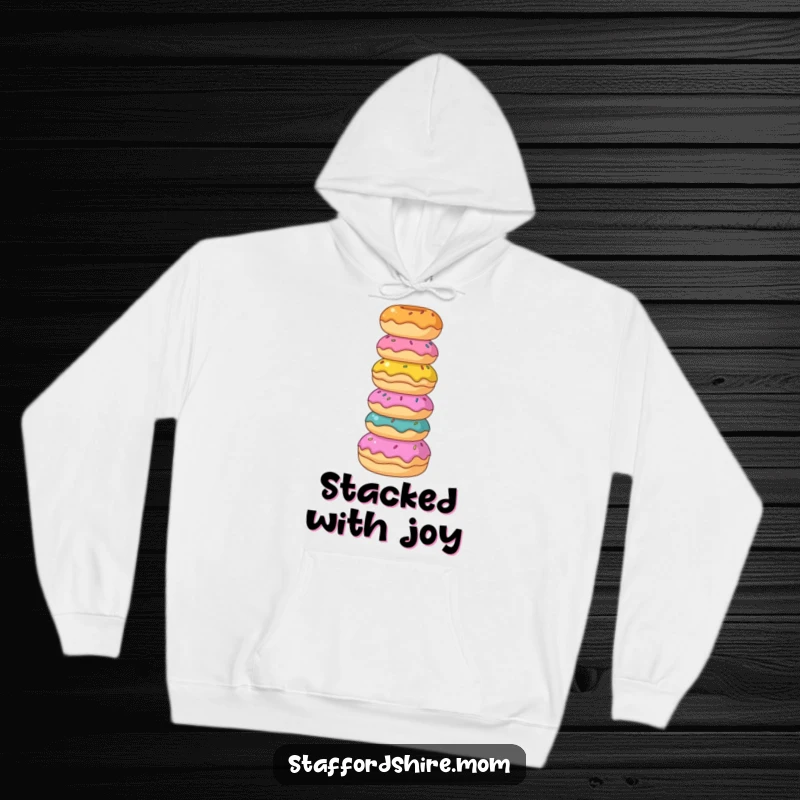 Funny Staffordshire hoodie, a dog balances colorful donuts, offering sweet comfort and playful vibes.